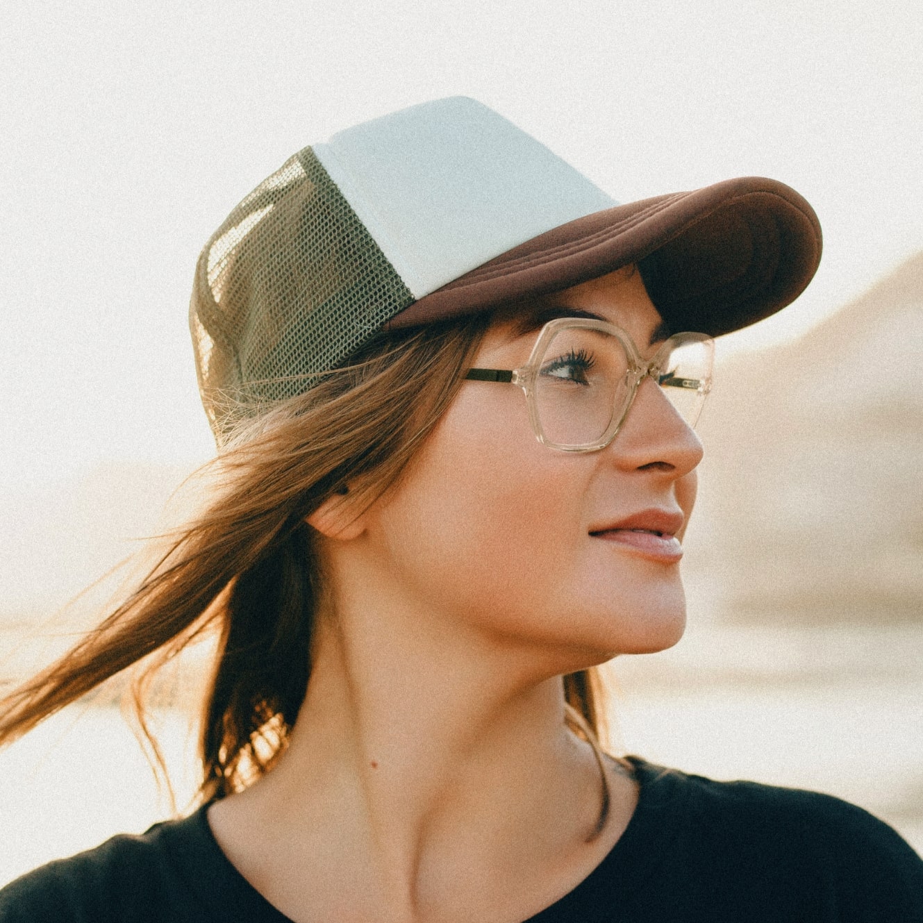 Femme de profil porte une casquette et des lunettes plastique translucides