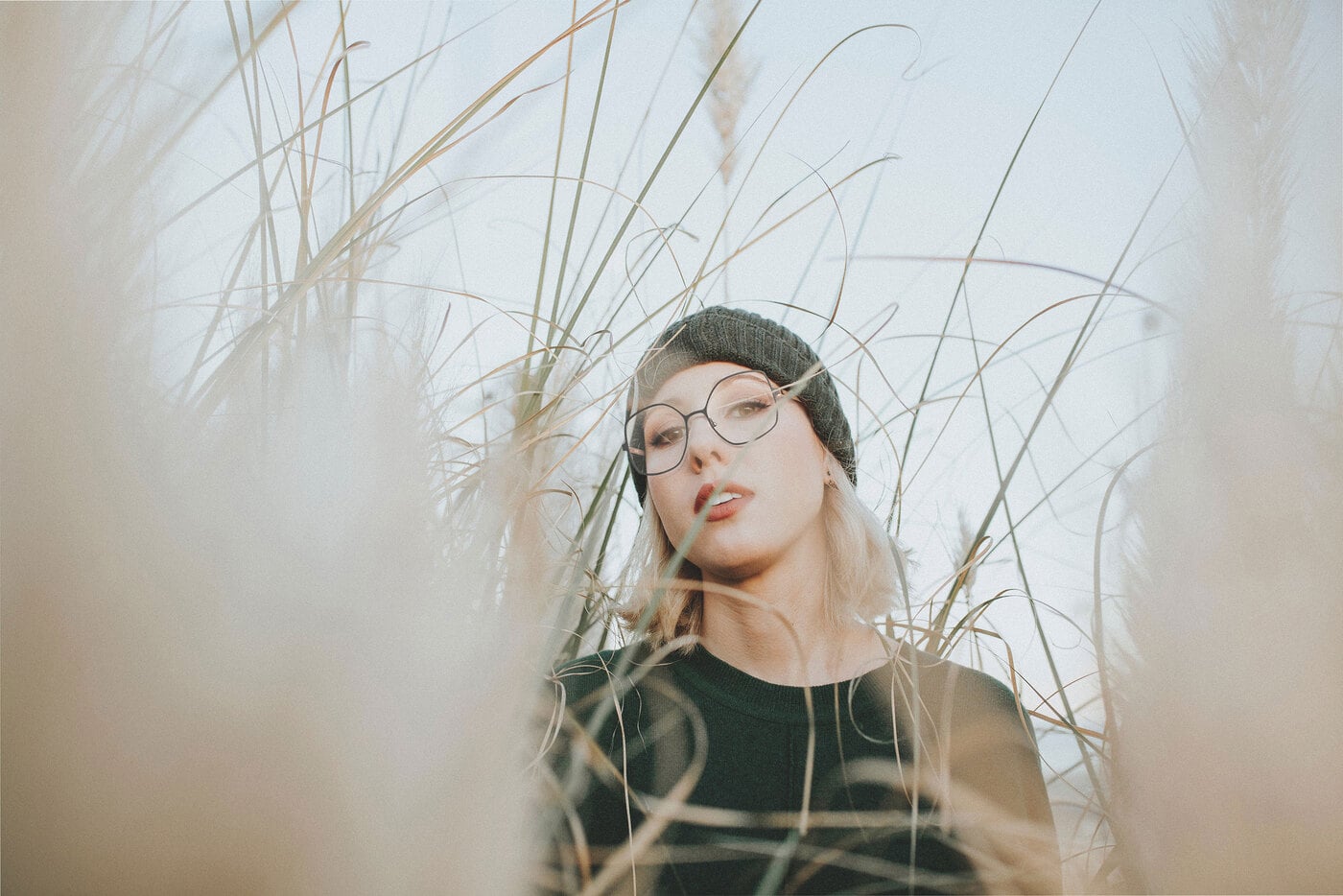 Visage femme avec bonnet dans les champs porte des lunettes en métal noir, fines, oversized